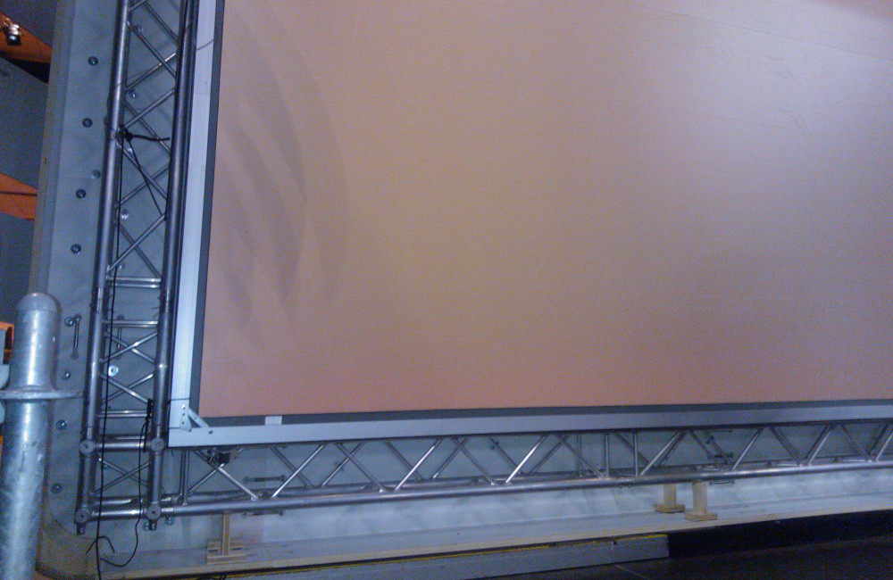 Bühnenkulisse mit tragendem Traversensystem und fertig montierter 8m breiten Rückprojektionsleinwand in der Messe Klagenfurt