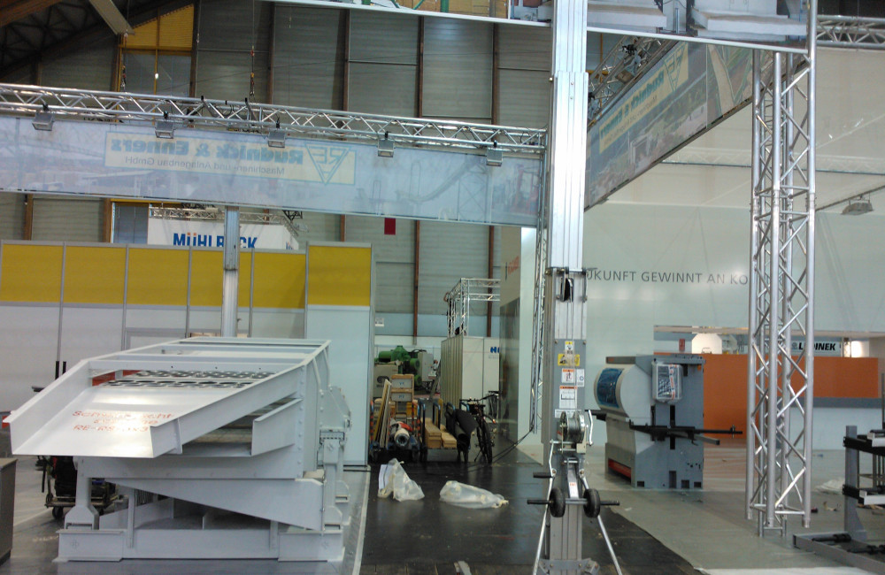 Rudnick & Enners Messestand Aufbau der Traversen, Banner und HQI Beleuchtung auf der Messe Holzbau in Klagenfurt