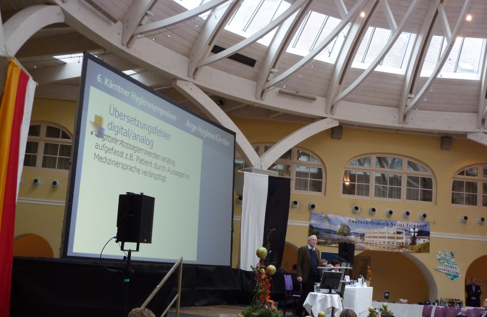 Konferenz Bühne mit Rückprojektion Meyer Sound PA und Rednerpult beim Hygienesymbosium im Krankenhaus Friesach