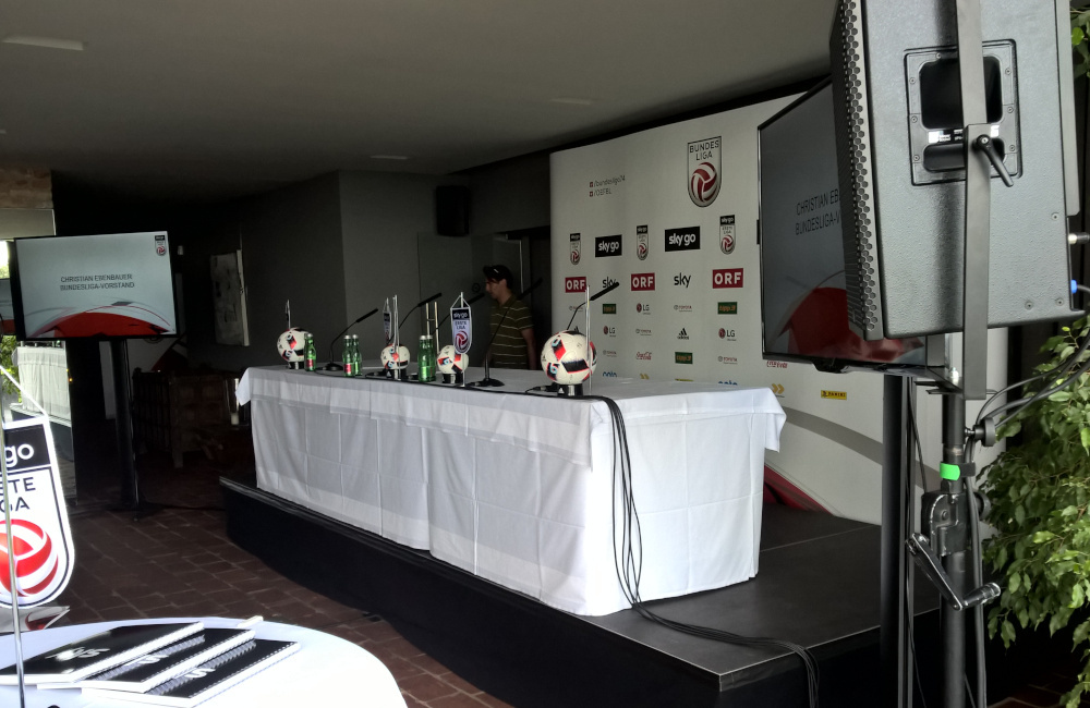 Konferenzbühne, Podium mit Schwanenhals Mikrofonen, Meyer Sound PA und Flat-TV auf SMS Stativ Weingut Reisinger für den ÖFB
